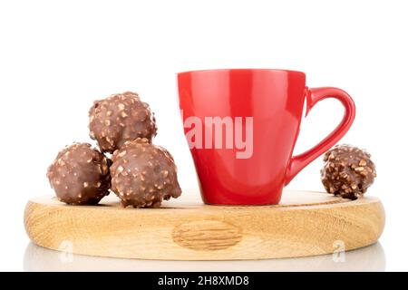 Due cioccolatini dolci con noci su un vassoio di legno con una tazza rossa, primo piano, isolato su bianco. Foto Stock