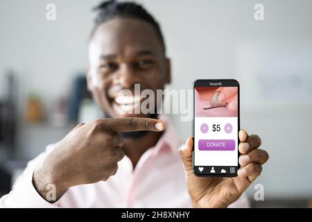 Uomo che utilizza l'app per cellulare Online Money Donation Foto Stock