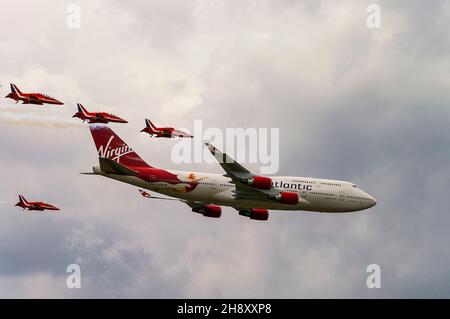 RAF Red Arrows jet che volano a fianco dell'aereo di linea Virgin Atlantic Boeing 747 Jumbo Jet G-VFAB al Biggin Hill Airshow. Scorta dell'Aeronautica reale Foto Stock