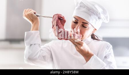 La cuoca femminile di rondon odora un taglio fresco di carne rossa con piacere. Foto Stock