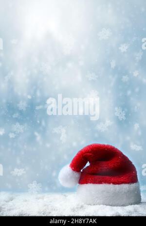 Cappello Babbo natale con neve e sfondo blu nevicata. Concetto di vacanza. Foto Stock