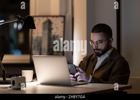 Web designer occasionale o programmatore ragazzo che lavora da solo in ufficio a tarda notte prima del lancio del progetto Foto Stock