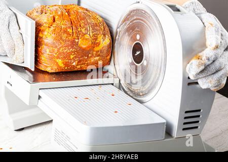 Primo piano immagine isolata che mostra un macellaio o chef affettare un grande blocco di carne surgelata. Pastirma turco, pastrama, prosciutto, manzo concetto. La persona w Foto Stock