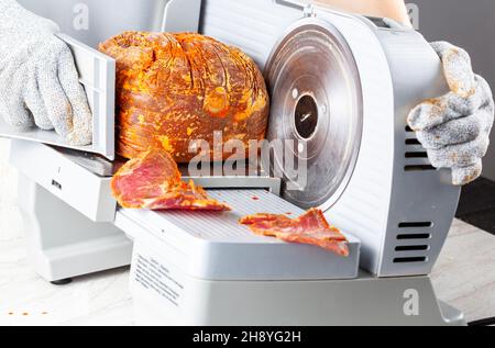 Primo piano immagine isolata che mostra un macellaio o chef affettare un grande blocco di carne surgelata. Pastirma turco, pastrama, prosciutto, manzo concetto. La persona w Foto Stock