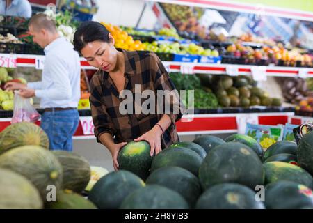 Donna che sceglie i meloni in gregrocer Foto Stock