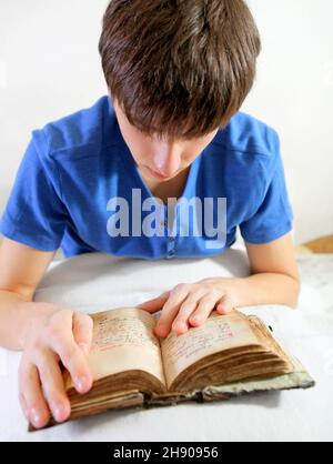 Giovane uomo ha letto il vecchio libro sul letto alla casa Foto Stock