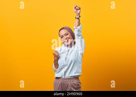 Ritratto di donna asiatica eccitata che celebra la fortuna su sfondo giallo Foto Stock