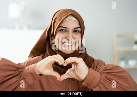 Donne musulmane romantiche che fanno la forma della mano del cuore Foto Stock