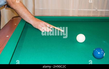 Un primo piano di un tavolo da biliardo con palle che puntano le mani dell'atleta prima di colpire. Foto Stock