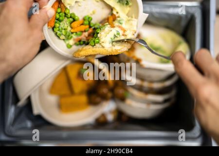 Gettando via cibo residuo nel cestino o nel cestino della spazzatura Foto Stock