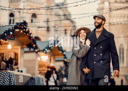 Le persone di Natale che camminano per Capodanno. Una giovane coppia felice d'amore che tiene le mani e cammina per la strada durante le vacanze di Natale. Foto Stock