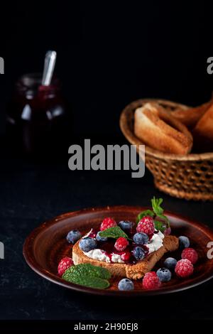 Bruschetta con formaggio, marmellata, lamponi freschi e mirtilli Foto Stock