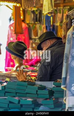 l'uomo più anziano stalla titolare ad un mercato di natale in southampton che vende i cappelli colorati e scsrves, commerciante di mercato ad un mercato di natale, cappelli del detentore di stalla Foto Stock