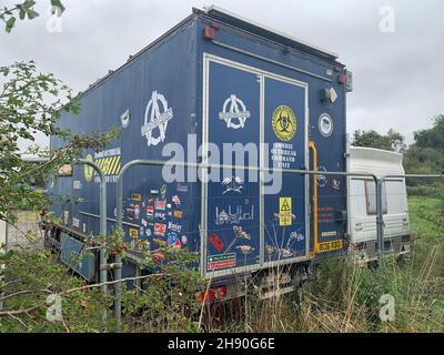 Autocarro presso l'autodromo di Santa Pod Poddington Bedfordshire Regno Unito barriere barriera recinzione segnali campo caravan sonno tempo di sonno estate erba cespuglio arte Foto Stock