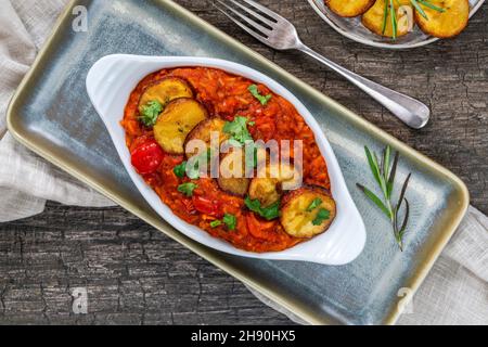 Riso Jollof con plantain fritto - piatto piccante di riso africano vegetariano Foto Stock