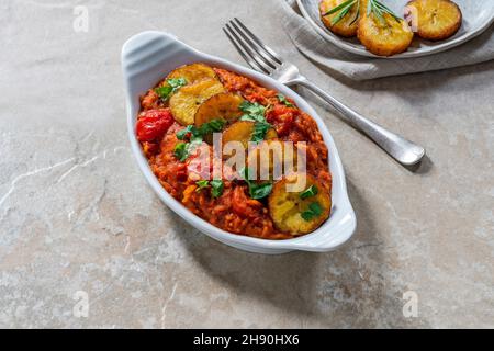 Riso Jollof con plantain fritto - piatto piccante di riso africano vegetariano Foto Stock