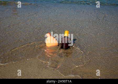 Primo piano di protezione solare posto sulla spiaggia di sabbia sul mare tropicale in una calda giornata di sole. Concetto di cura della pelle Foto Stock