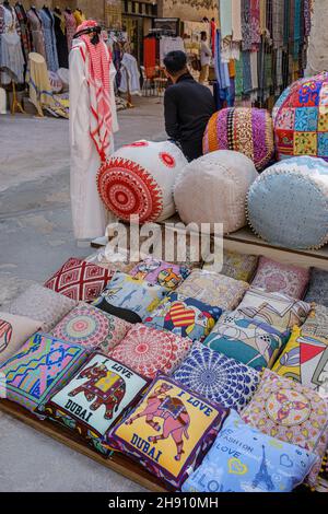 Cuscini ricamati colorati in vendita all'esterno di un negozio di souvenir a al Seef, Dubai Foto Stock