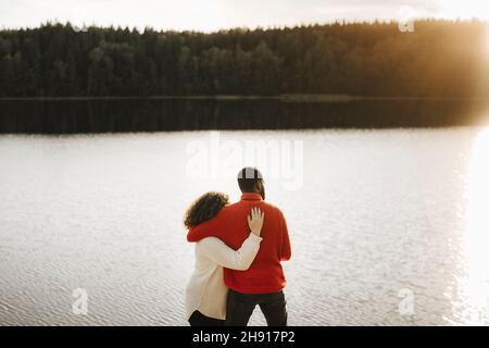 Coppia abbracciante mentre si guarda il lago Foto Stock