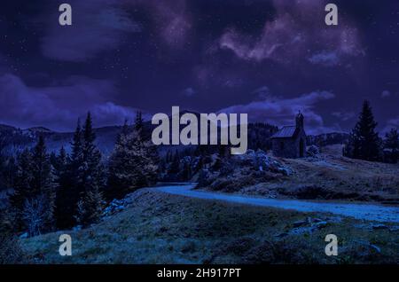 Notte stellata in una valle di montagna. Cappella di pietra e strada di montagna in montagna Velebit montagne, Velebit Nord Parco Nazionale, Croazia Foto Stock