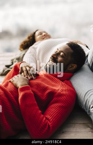 Coppia eterosessuale sorridente che si rilassa sul molo Foto Stock