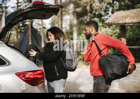 Coppia multirazziale carico bagagli in bagagliaio auto durante le vacanze Foto Stock