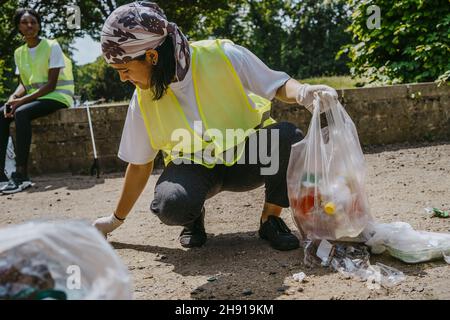 Giovane femmina volontaria raccolta rifiuti di plastica nel parco Foto Stock