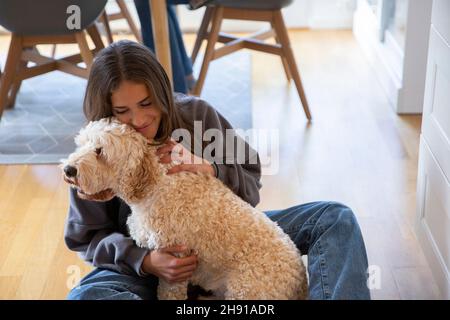 Ragazza che abbraccia il cane a casa Foto Stock
