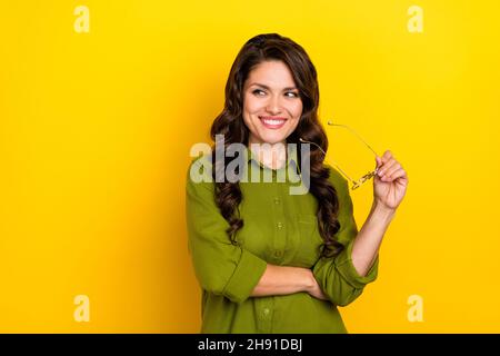 Foto di agente banchiere intelligente signora take off specifiche guardare spazio vuoto indossare camicia verde isolato giallo sfondo colore giallo Foto Stock