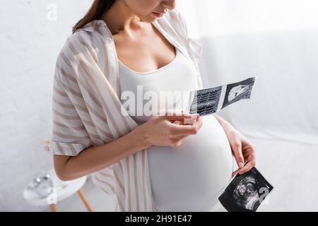 vista parziale di una donna incinta con foto a ultrasuoni Foto Stock
