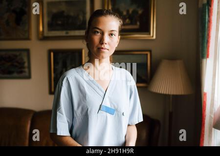 Ritratto di infermiera femminile in soggiorno a casa Foto Stock