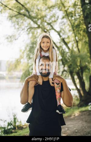 Ritratto di padre che porta la figlia in spalla nel parco Foto Stock