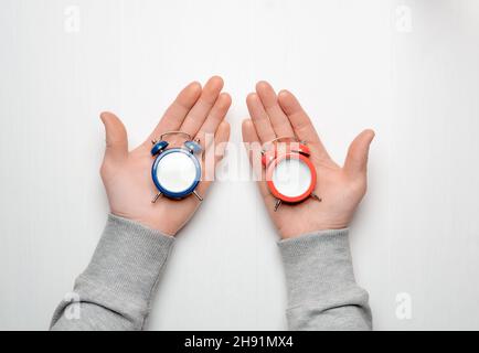 Le mani maschili stanno tenendo canne da pesca blu e rosse con quadranti bianchi. Poster vuoto. Concetto di scelta. Foto Stock