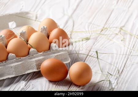 Materie organica marrone le uova di gallina in eco-friendly cartone carta sulla cucina bianca tavolo in legno Foto Stock