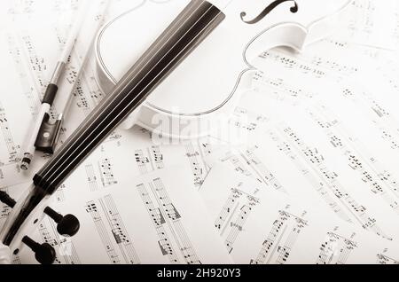 Chiudere la vista di un violino e note musicali su bianco tavolo in legno Foto Stock