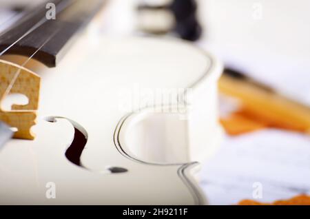 Chiudere la vista di un violino e note musicali su bianco tavolo in legno Foto Stock