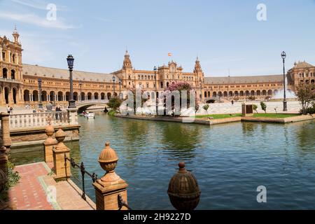 Siviglia, Andalusia, Spagna - 12 agosto 2021: Edificio rinascimentale centrale in piazza Plaza de Espana, vista sul fiume Guadalquivir con barche e gente Foto Stock