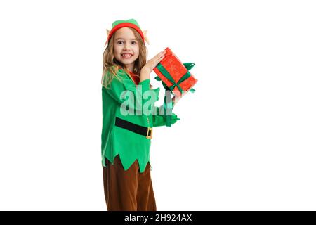 Ritratto di ragazza piccola felice vestito come divertente gnome o elfo tenendo rosso scatola regalo isolato su sfondo bianco studio. Foto Stock