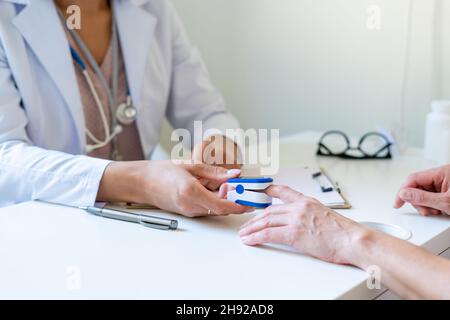Medico femmina corto che misura la saturazione di ossigeno di pazienti anonimi con pulsossimetro Foto Stock