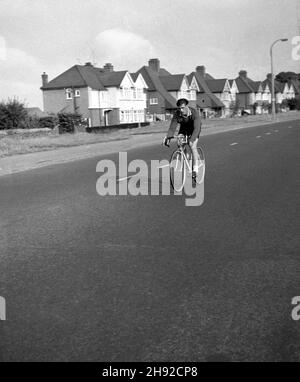 1960, storico, un pilota maschile su una strada extraurbana aperta che partecipa a una gara ciclistica, Essex, Inghilterra, Regno Unito. Foto Stock