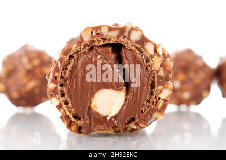 Due caramelle al cioccolato intere e mezzo con noci, primo piano, isolate su bianco. Foto Stock