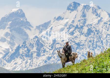 ALAMEDIN, KIRGHIZISTAN - 21 MAGGIO 2017: Pastore su un cavallo con il suo cane in un pascolo nella valle di Alamedin. Foto Stock