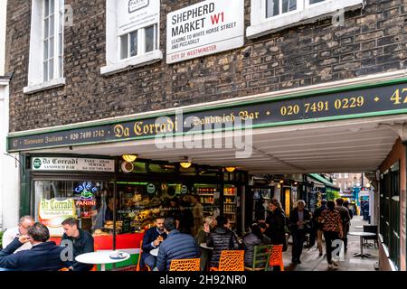 Persone che siedono all'esterno del da Corradi Sandwich Bar all'entrata del mercato del Pastore, Londra, Regno Unito. Foto Stock
