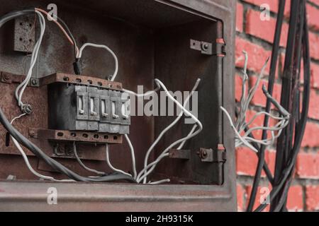 La nicchia del vecchio quadro elettrico rotto del cassetto sulla parete. Controllo della potenza industriale abbandonata. Foto Stock