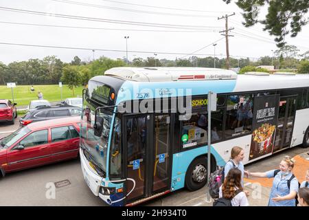 Gli studenti di una scuola secondaria di Sydney aspettano il loro bus scolastico alla fine della scuola, Sydney, Australia Foto Stock