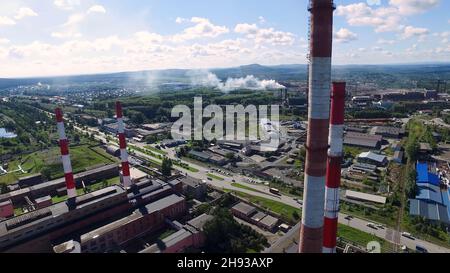 Vista panoramica dall'alto del panorama industriale dei tubi tecnologici e degli impianti. Riprese. Produzione industriale su sfondo di città e dis Foto Stock