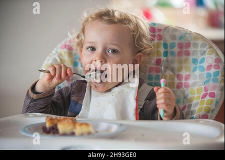 Bambina di 1 anno mangia Panettone. Carino ragazza caucasica che tiene la torta  di Pasqua. Sviluppo del bambino di un anno Foto stock - Alamy