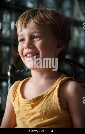 Un ragazzo di 4 anni reagisce mentre guarda un cartone animato sullo schermo di un computer a casa. Foto Stock