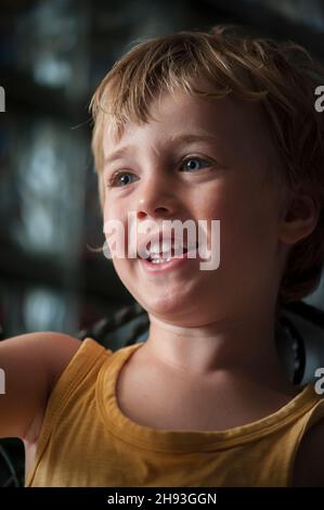 Un ragazzo di 4 anni reagisce mentre guarda un cartone animato sullo schermo di un computer a casa. Foto Stock