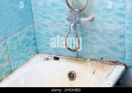 Il bagno, la doccia, il rubinetto dell'acqua e le piastrelle erano molto sporchi. Vasca da bagno bianca molto sporca. La vasca da bagno deve essere pulita. Vasca grimy. Piastrelle blu con un motivo Foto Stock